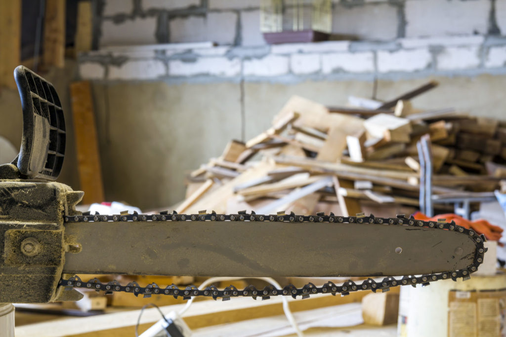 Closeup view of a chainsaw bar and cutting chain at construction site.